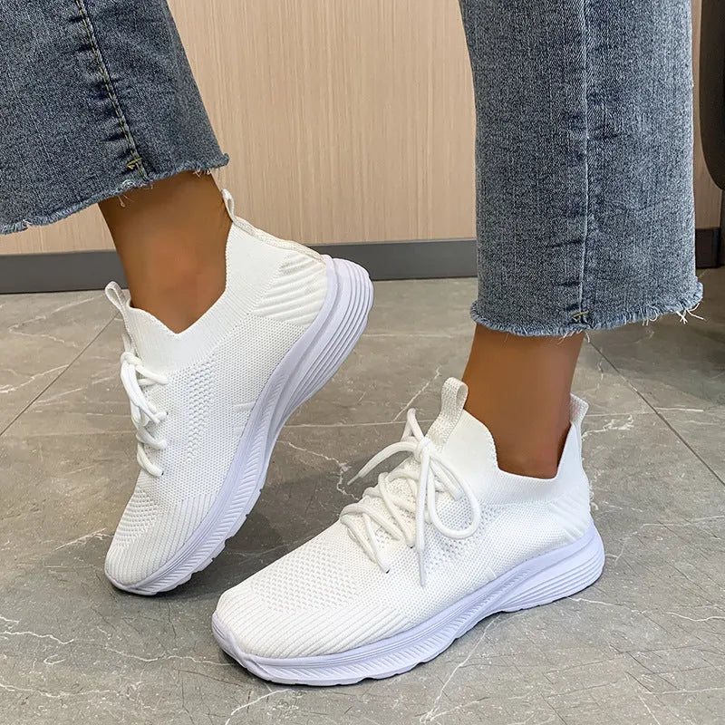 Women's low-top running shoes in Flyknit mesh, shown in creamy white colour with flat rubber sole.