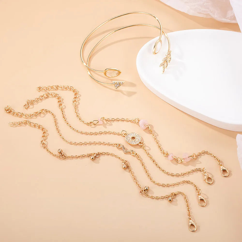Gold-coloured women's bracelet set with six charms: arrow, water drop, and V shapes.