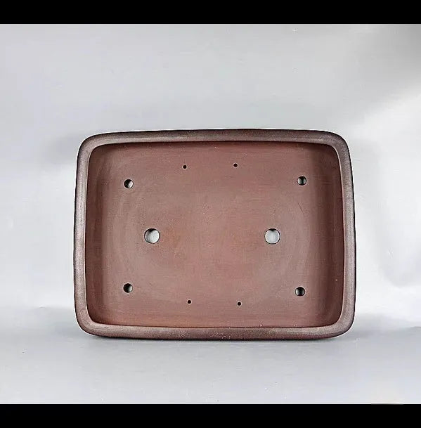 Large handmade antique rectangular purple clay flower pot on a table.