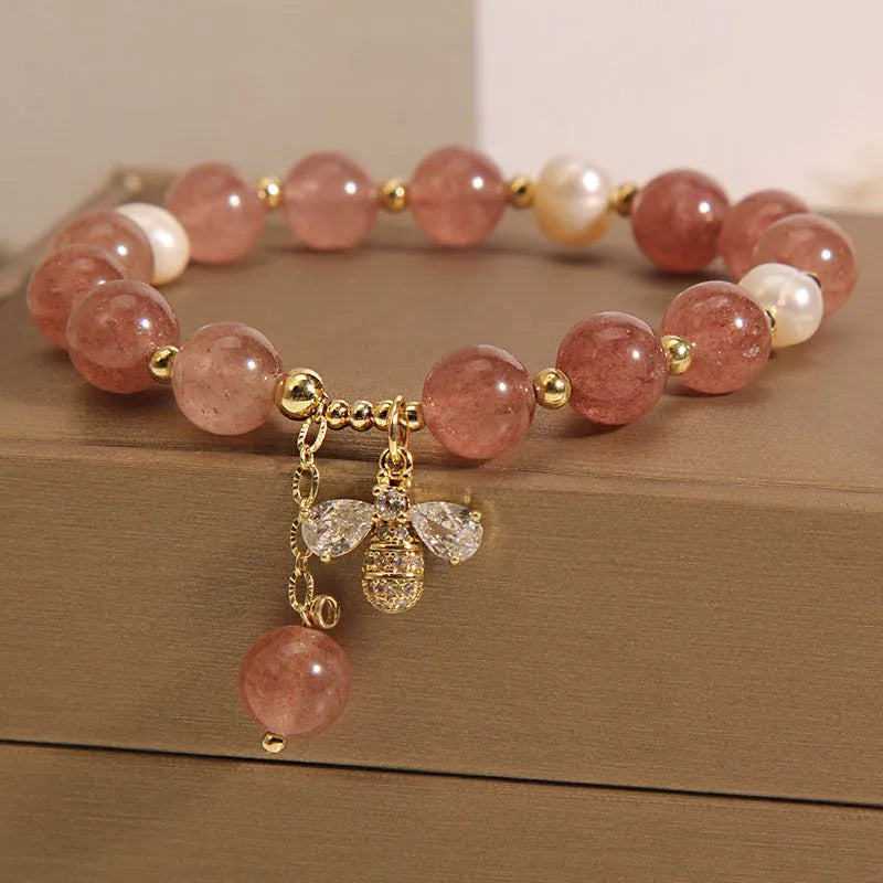 Women's bracelet with strawberry quartz beads, freshwater pearls, and a bee charm.