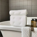 White bathtub pillow with mesh fabric and suction cups on a bath mat.