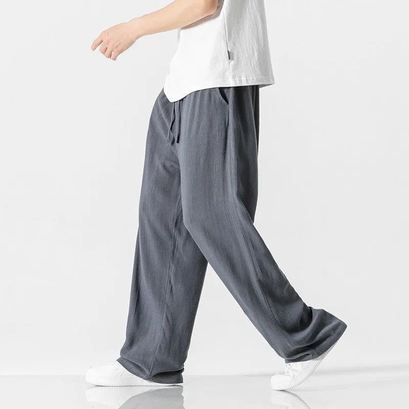Man modelling beige linen drawstring trousers with a straight-leg cropped fit.