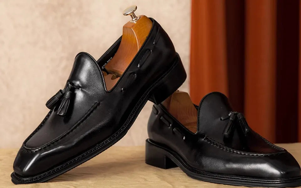 Men's black genuine leather slip-on loafers showing polished finish and rubber sole