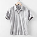 A man's loose-fit linen casual shirt in a solid colour, shown in light grey, featuring long sleeves and a button front.
