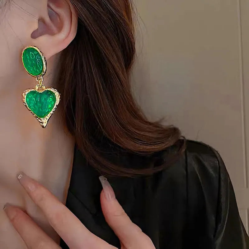 A pair of alloy pleated oval heart-shaped stud earrings with silver posts on a white background.