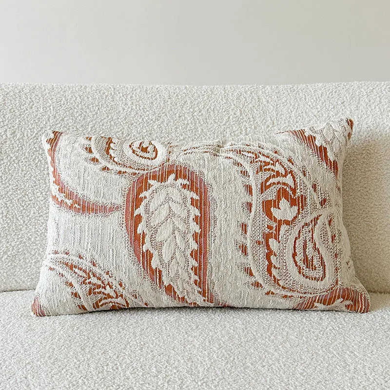 Amber paisley patterned jacquard sofa cushion cover on a sofa, showing textured fabric and plant motif.