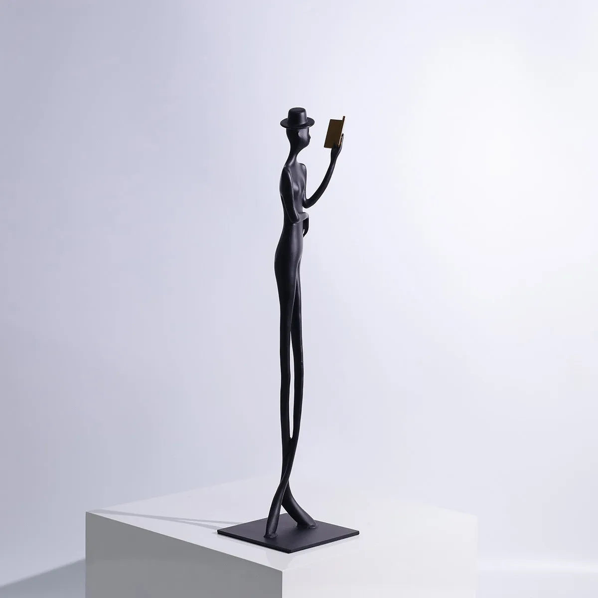 Black aluminium reading woman desk sculpture measuring 12cm by 12cm by 51cm