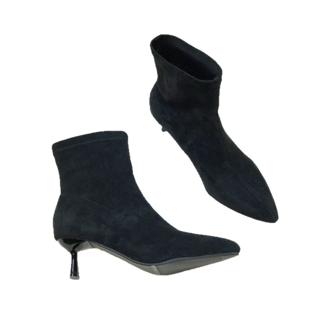 Black pointed toe stiletto heel ankle boots with a calf-high shaft on a neutral background.