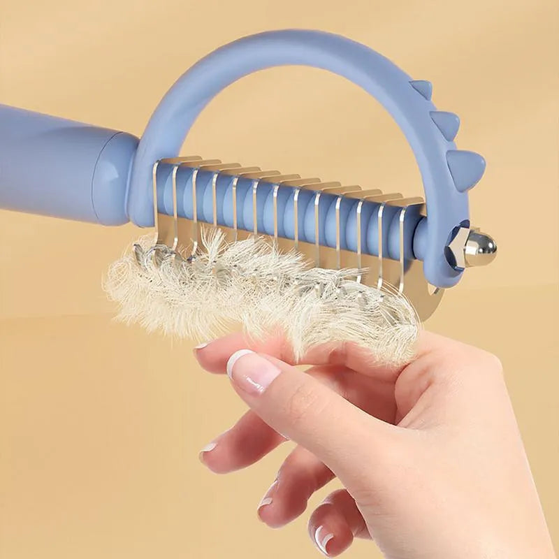 Blue dinosaur-shaped self-cleaning cat brush with double-sided slicker head.