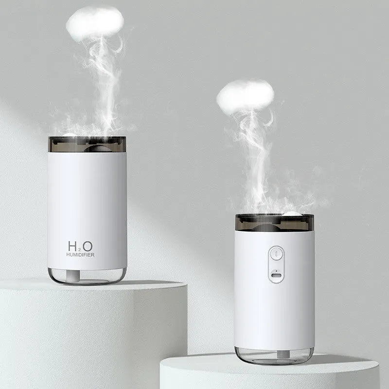 White jellyfish-shaped USB humidifier emitting smoke ring mist with warm night light glow on a table.