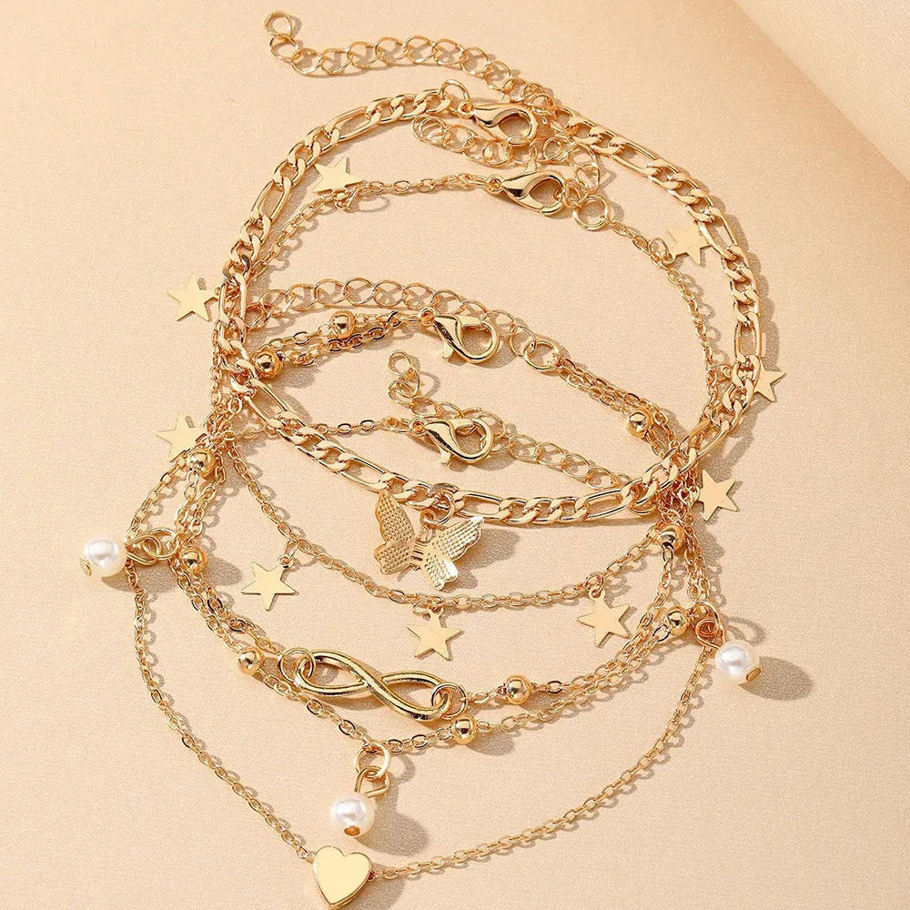 Four different alloy anklets with butterfly and pearl heart pendants arranged as a jewellery set