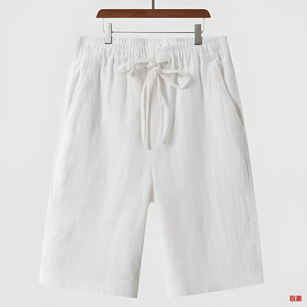 Men's beige linen casual shorts with loose cropped fit and elastic waistband on a neutral background.