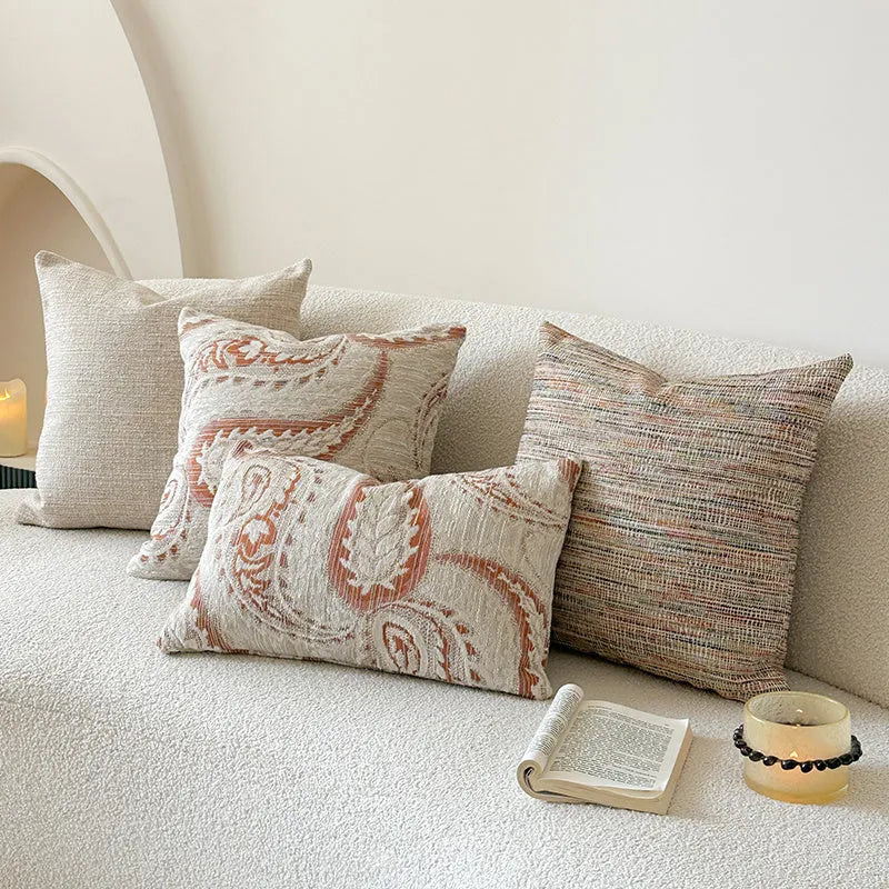 Amber paisley patterned jacquard sofa cushion cover on a sofa, showing textured fabric and plant motif.
