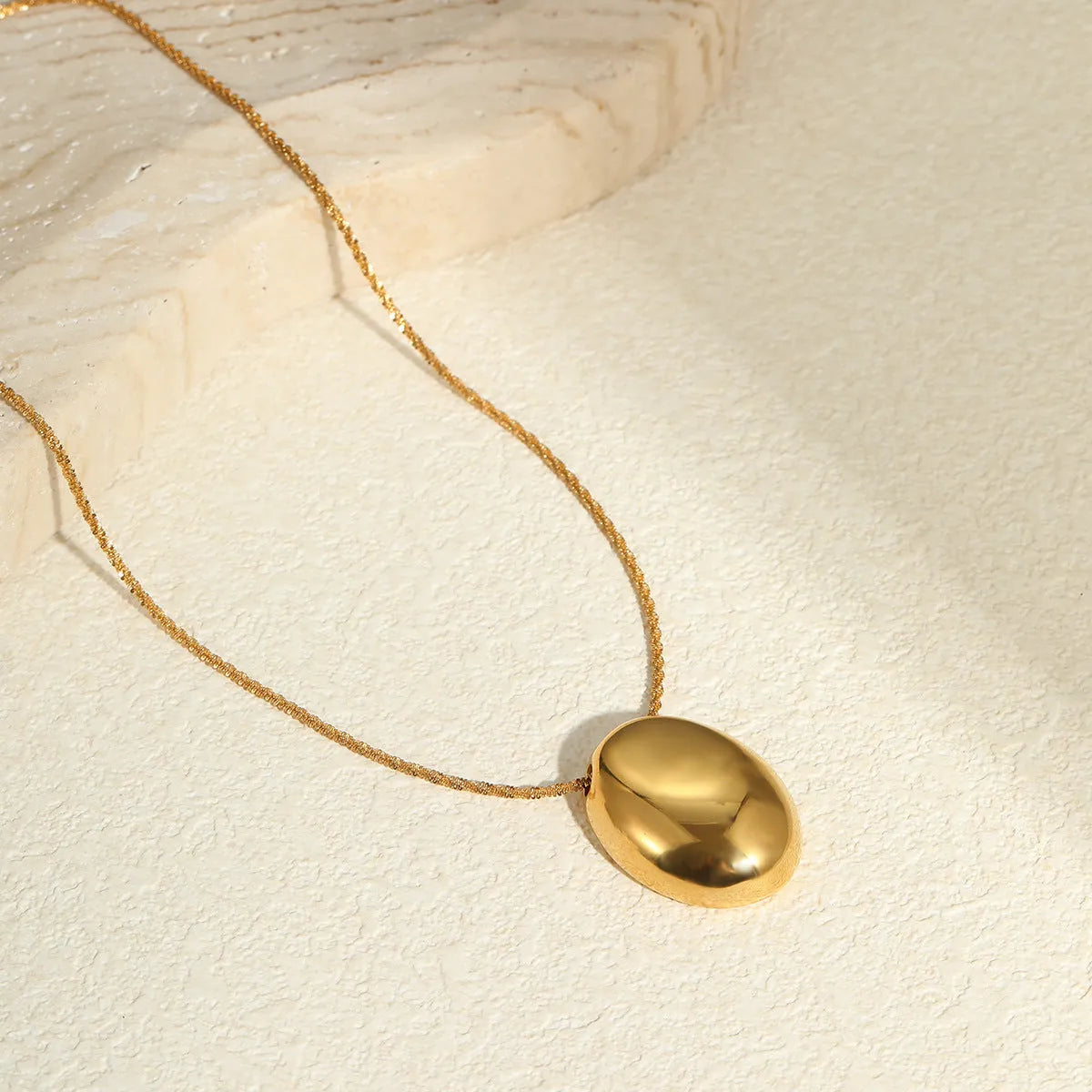 Geometric gold-plated pendant necklace with adjustable chain on white background