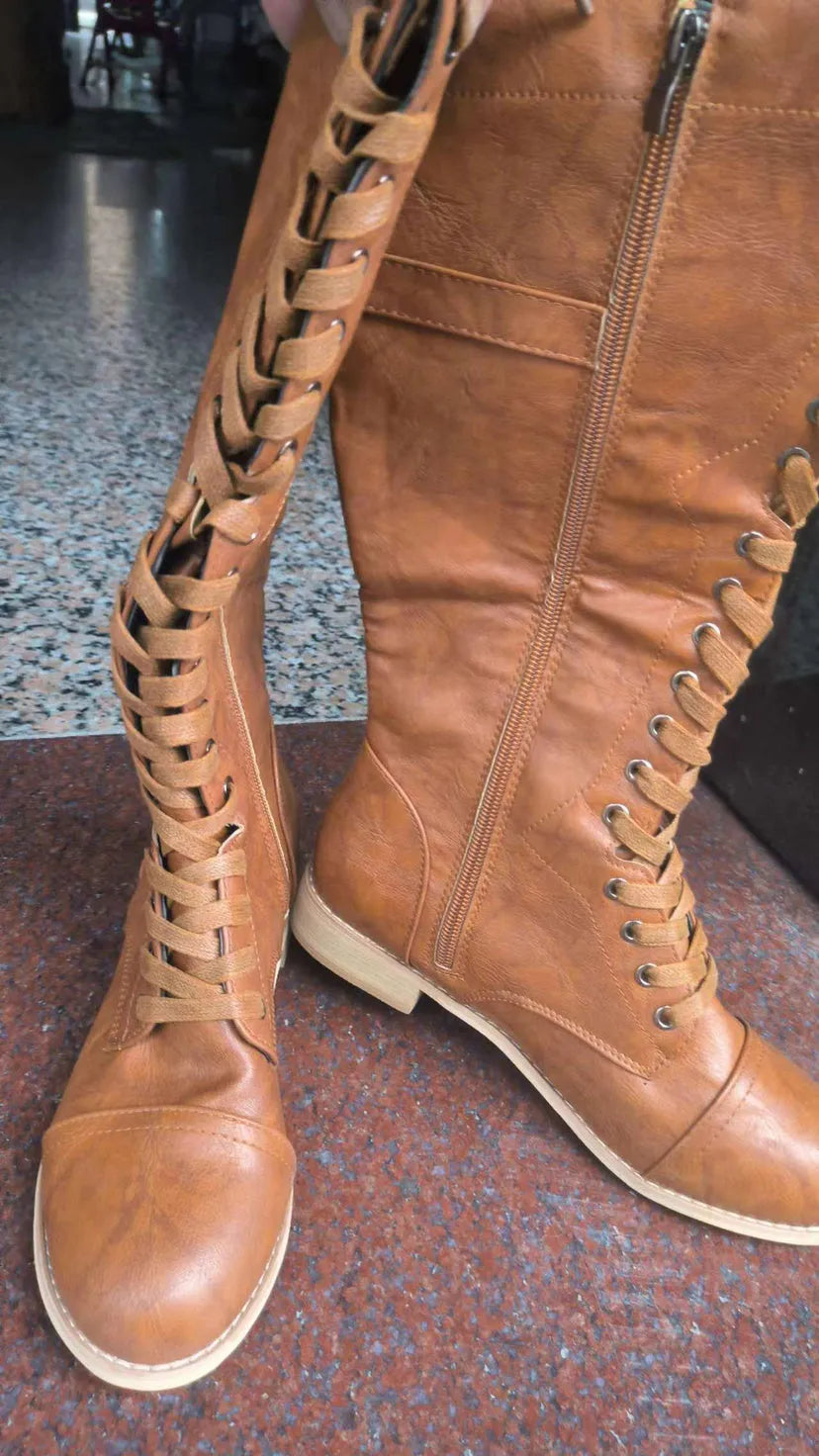 Women's black knight ankle boots with a cross strap detail on the ankle.