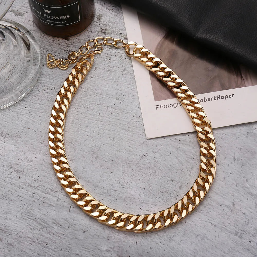 Gold coloured thick chain necklace for women on a white background.