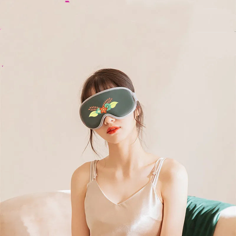 Green portable eye SPA mask with suede shell on a table, showing USB port and steam vents.