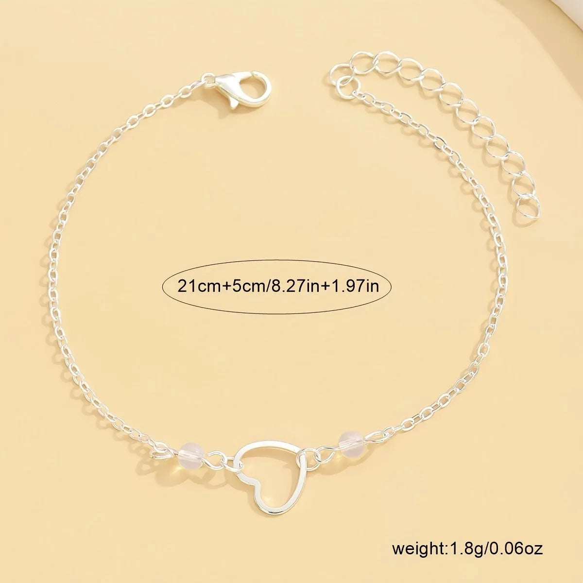 Adjustable gold or silver alloy anklet with a simple heart-shaped pendant.