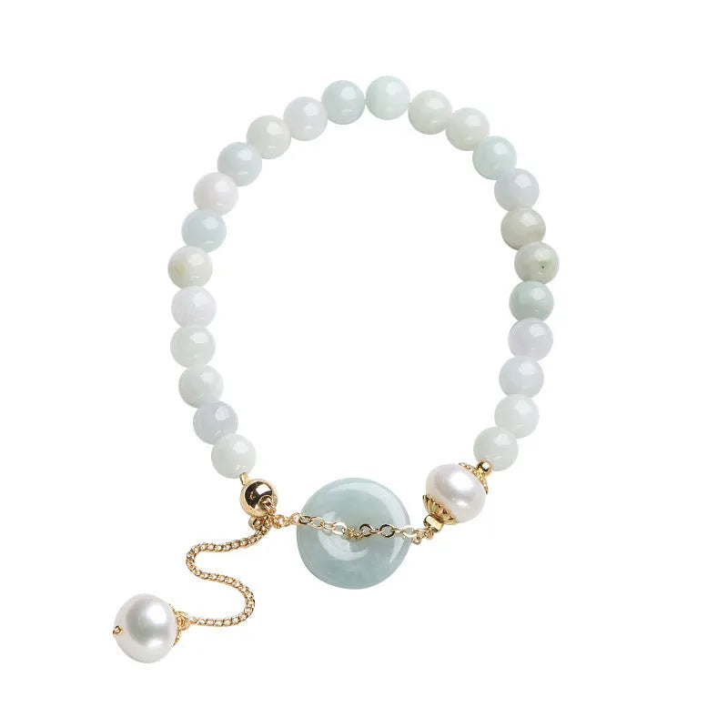 Close-up of a green jade and pearl bracelet with a geometric peace buckle on an elastic band.