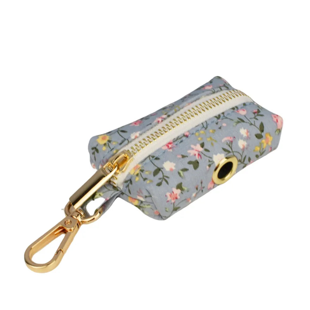 Blue floral patterned dog collar and matching leash, vest, and bow set on a white background.