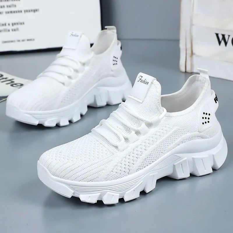 Women's white Flyknit sneakers with thick PVC sole and lace-up design on a neutral background.
