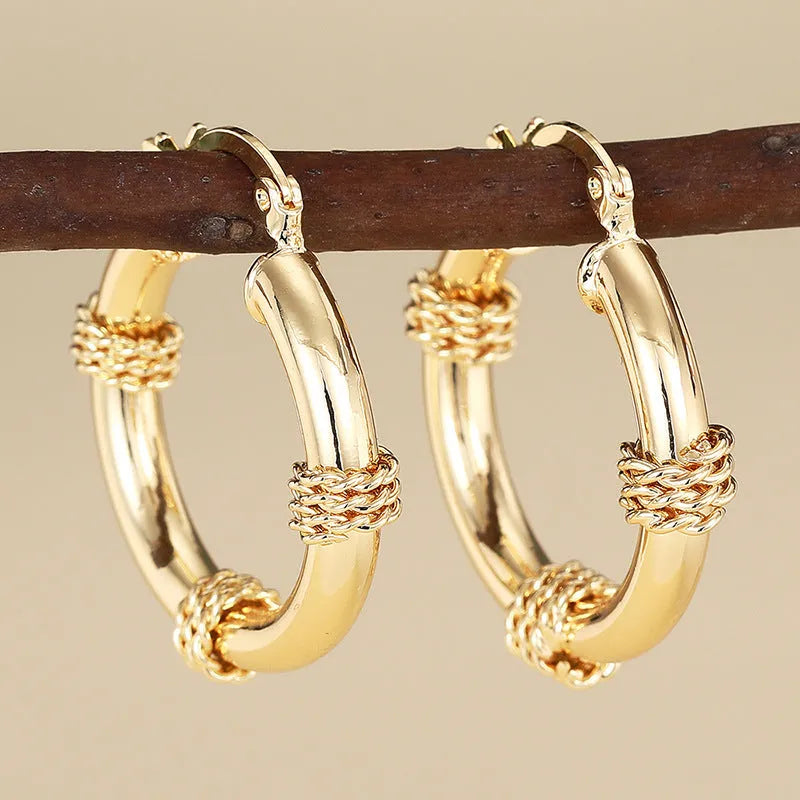 Geometric golden copper earrings with ear clip fastening showing ring and line design elements