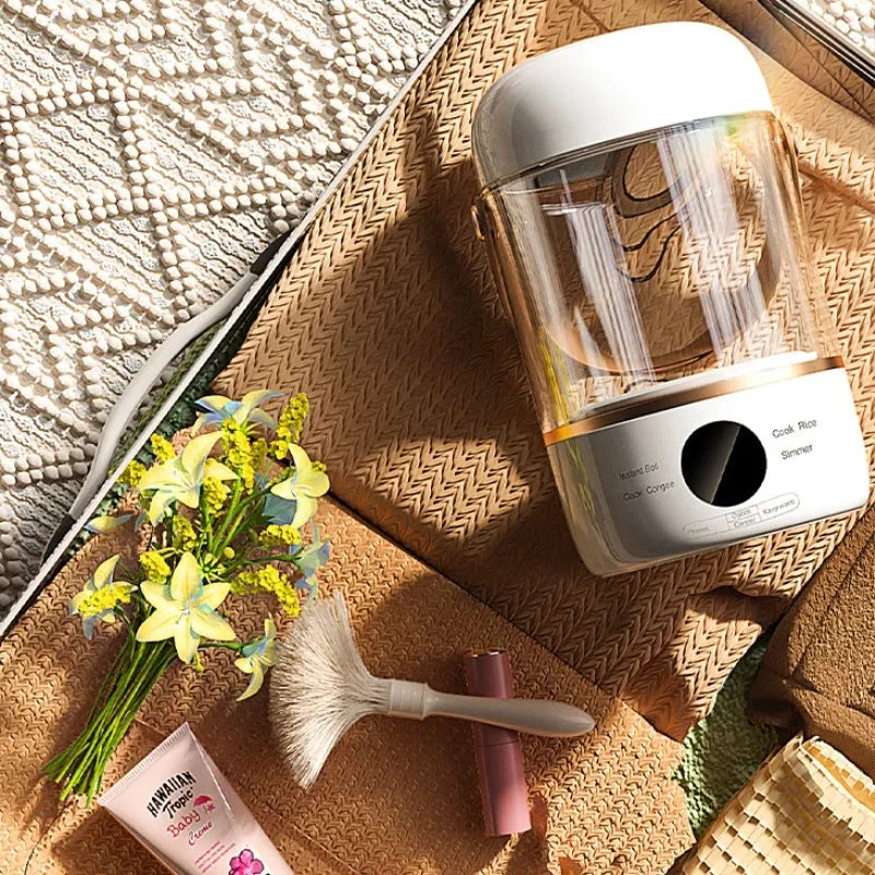 Personal portable electric stew cooker with transparent glass pot and fibreglass body on a counter.