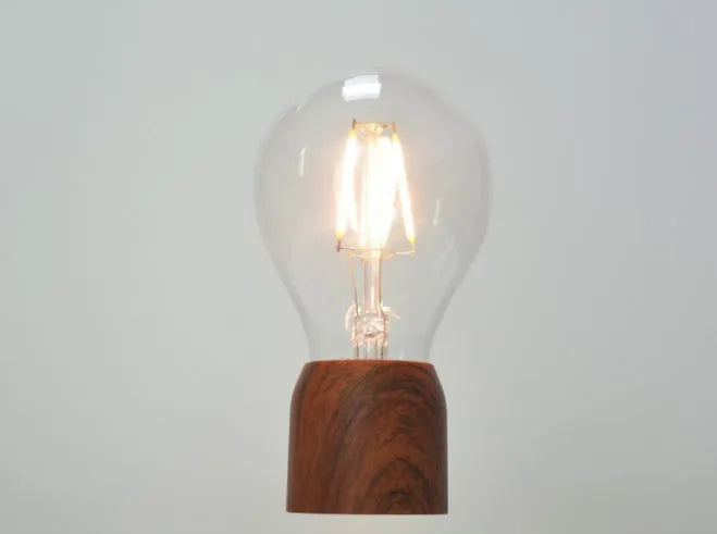 Magnetic levitation light bulb with imitation wood base on table.
