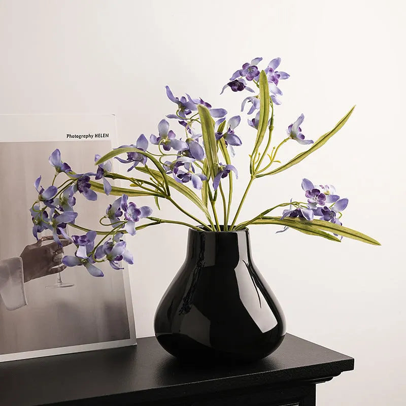 Ceramic round belly vase with coloured glaze finish in black or white, shown with artificial orchid stems