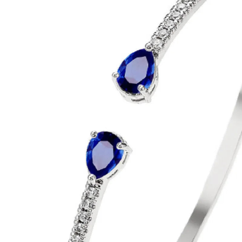 Close-up of a simple copper bracelet with inlaid blue zircon stones on a white background.