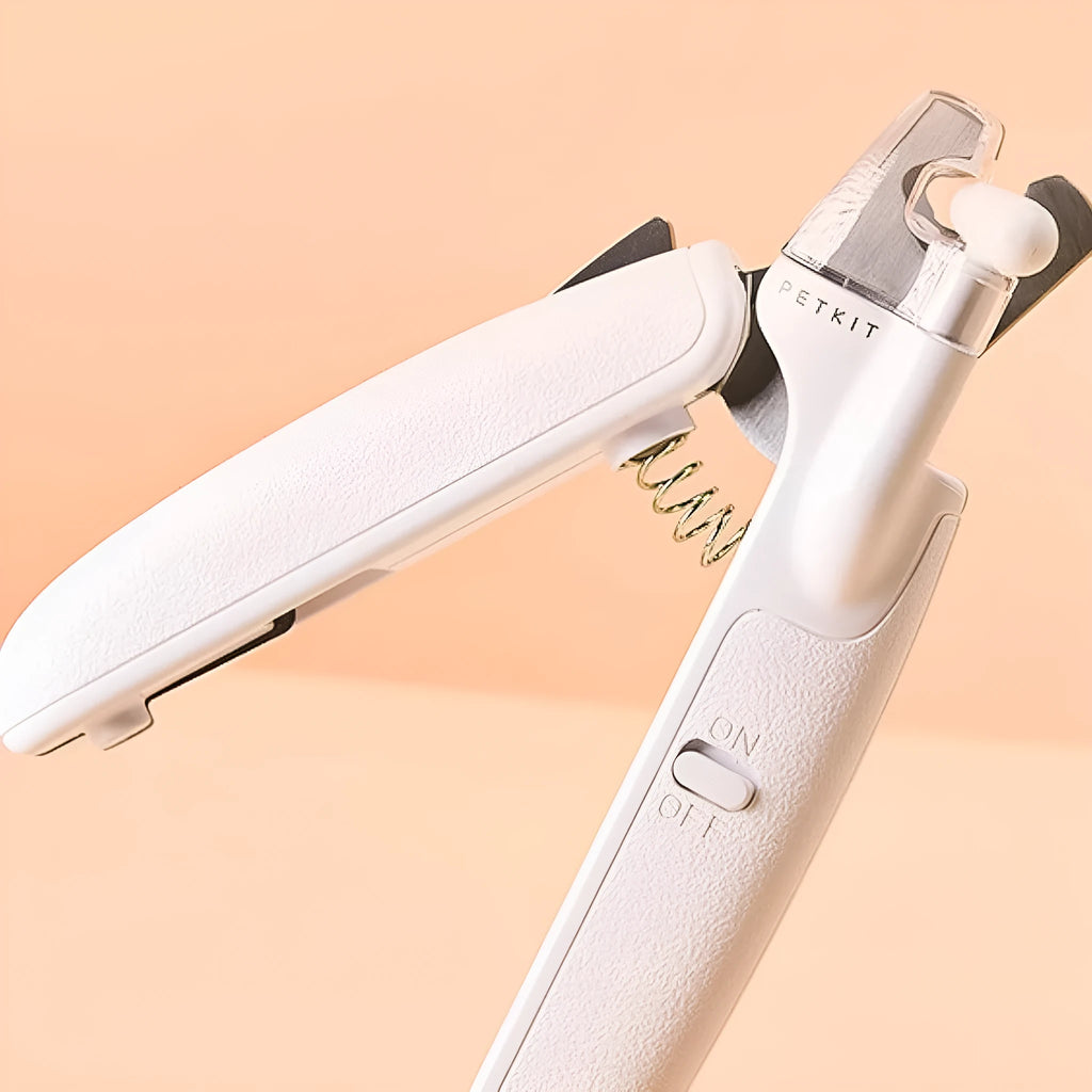 White LED pet nail clippers with transparent guard, triangular blade, and anti-slip handle next to a filing tool.