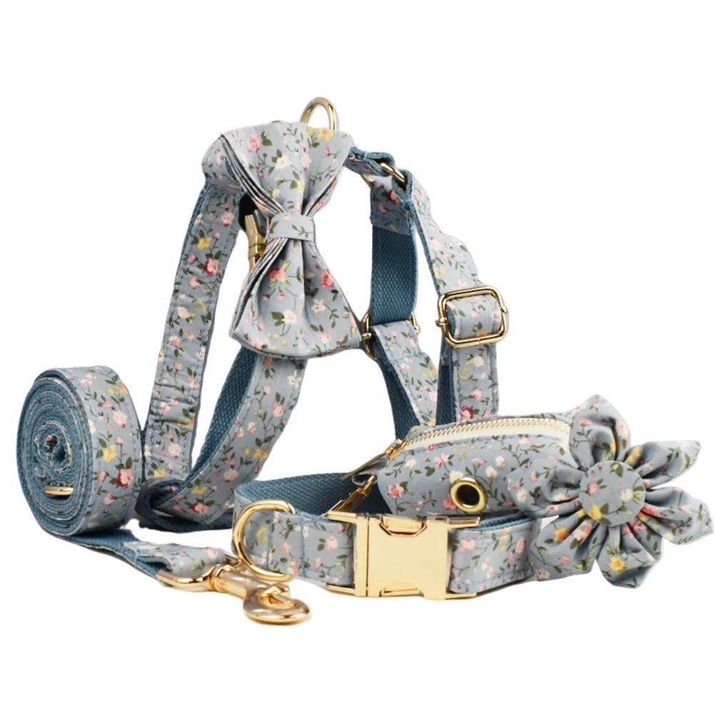 Blue floral patterned dog collar and matching leash, vest, and bow set on a white background.
