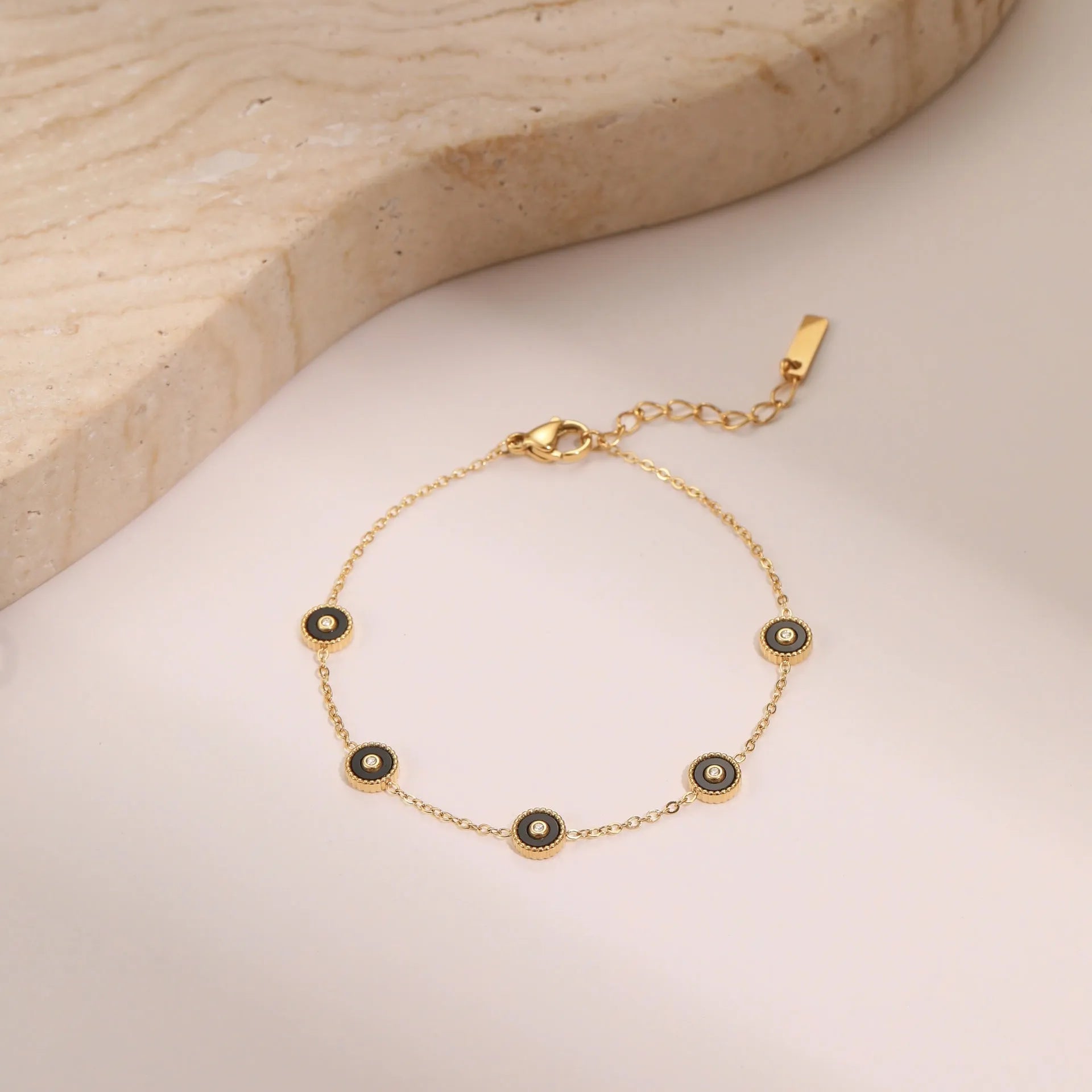 Close-up of a women's geometric fritillary pattern bracelet and necklace set in gold-plated stainless steel.
