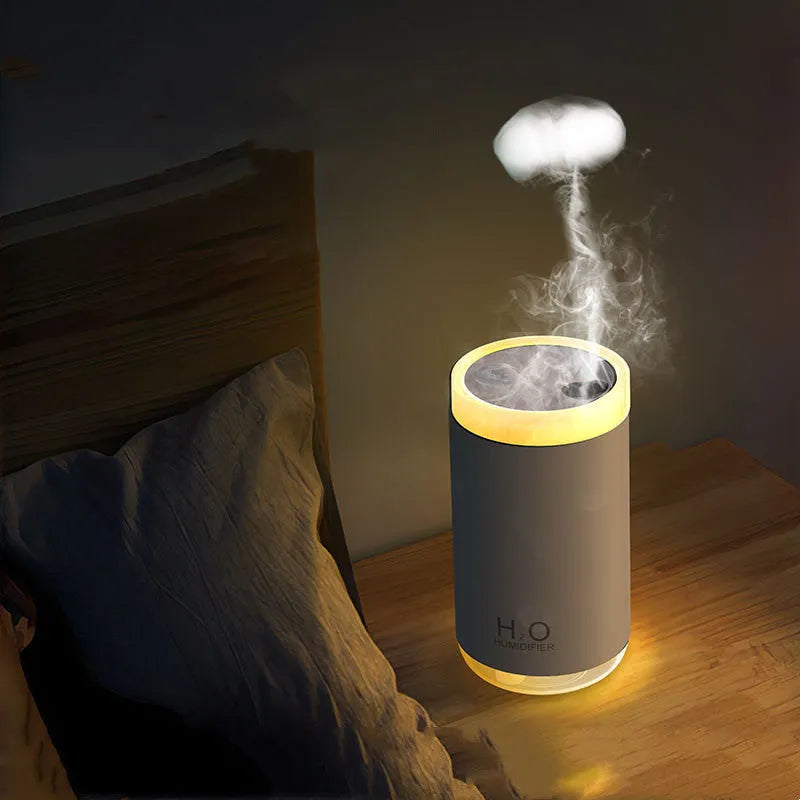 White jellyfish-shaped USB humidifier emitting smoke ring mist with warm night light glow on a table.