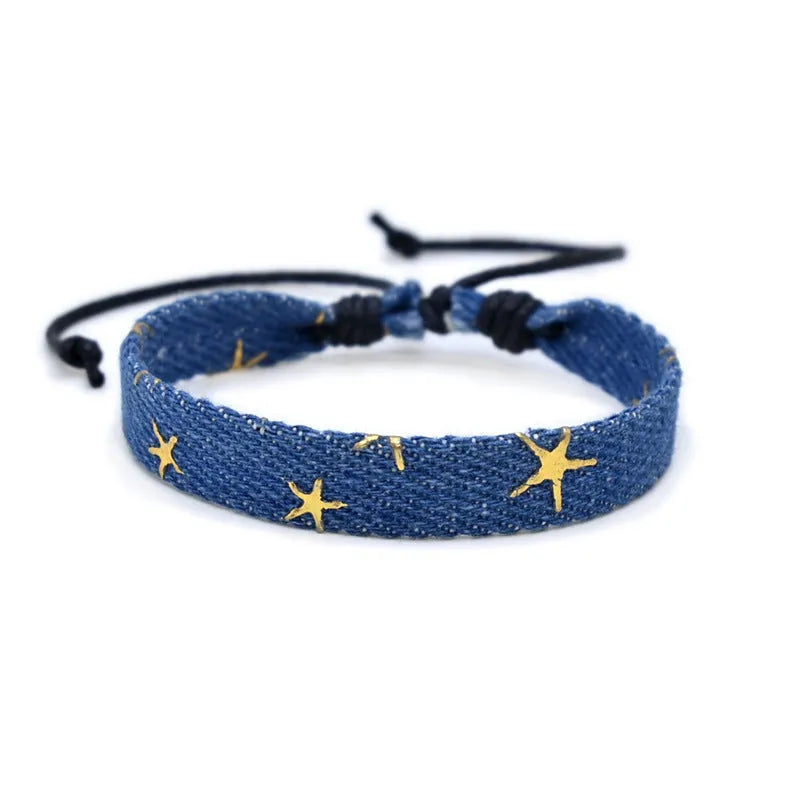 Handmade denim fabric bracelet carrying strap in national style on wrist, showing charm attachment point.