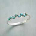Silver bubble ring with eight-leaf green agate stone on a plain background