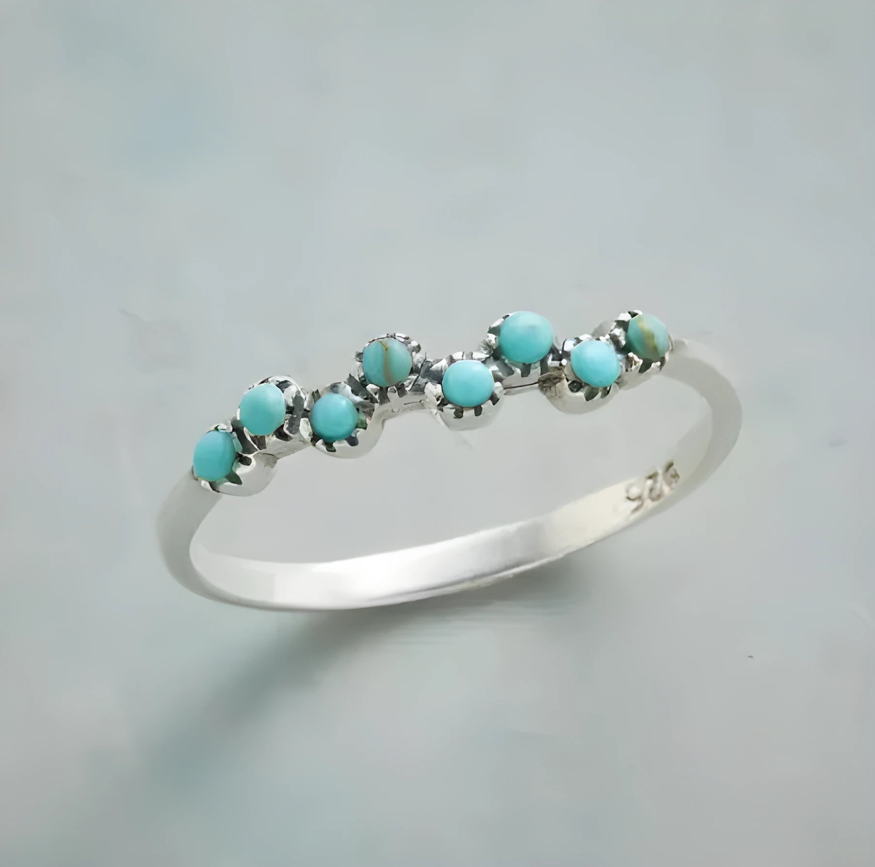 Silver bubble ring with eight-leaf green agate stone on a plain background