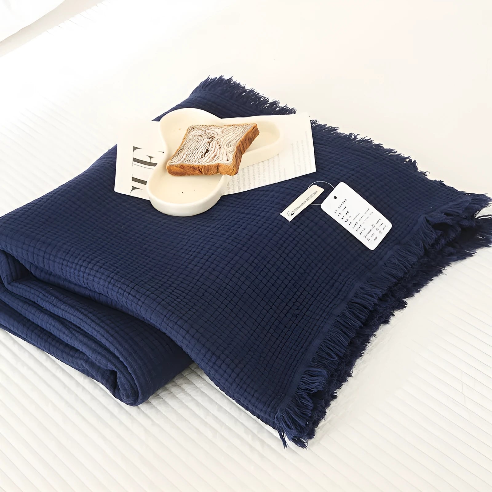 Four-layer cotton gauze blanket with tassel trim in avocado green colour laid flat.