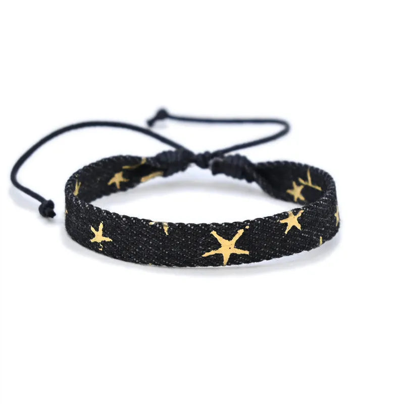 Handmade denim fabric bracelet carrying strap in national style on wrist, showing charm attachment point.