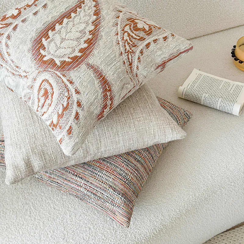 Amber paisley patterned jacquard sofa cushion cover on a sofa, showing textured fabric and plant motif.
