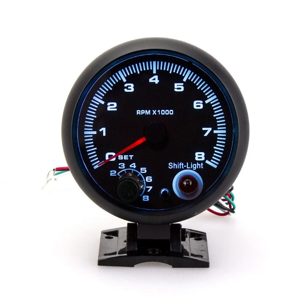 Black plastic automotive tachometer with blue-lit dial showing 0-8000 RPM scale.