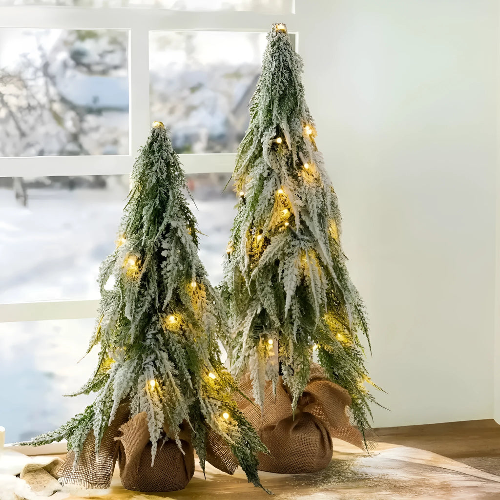 Small 24-inch artificial Christmas tree with snow sprayer finish and integrated lights on desktop