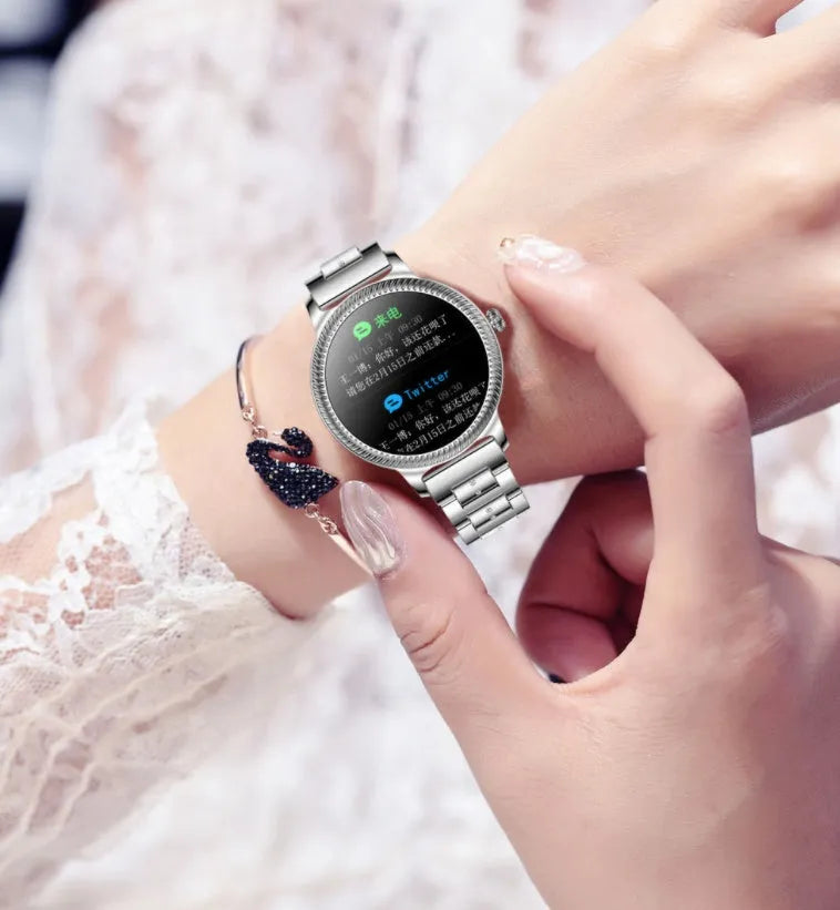 AK38 ladies smart watch with stainless steel Milanese band on wrist, showing its colour screen