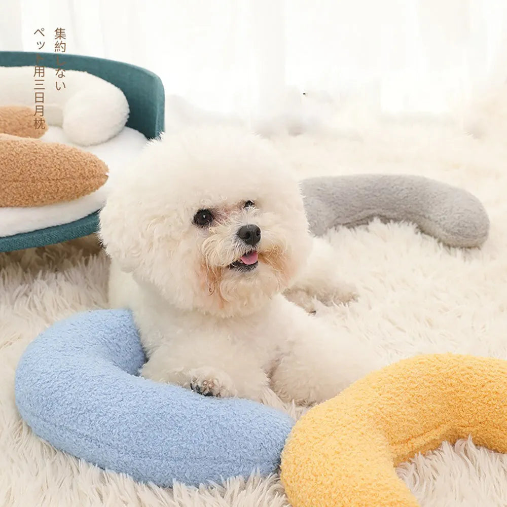 Blue U-shaped cat pillow with an adjustable fabric collar on a grey sofa.