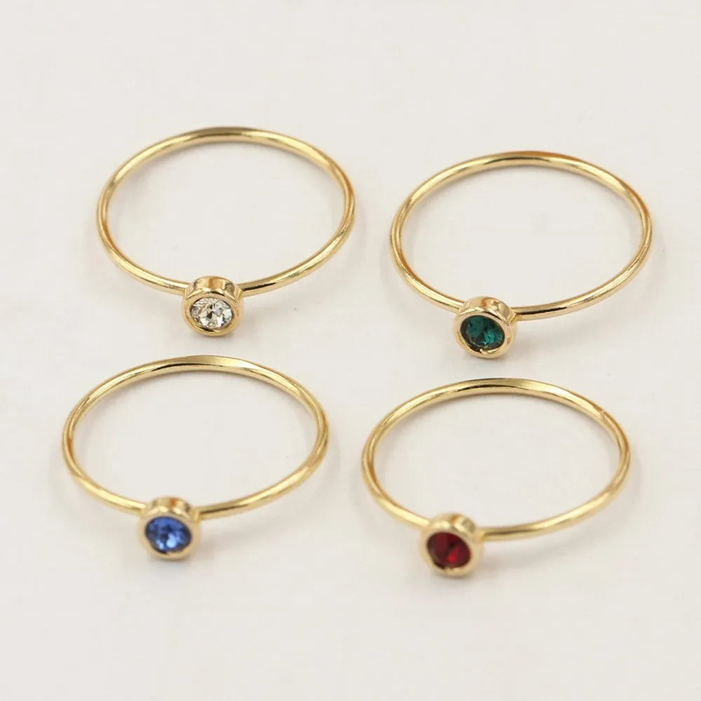 DIY knuckle ring craft kit showing 14K gold-plated ring base and green, blue, dark red, and white zircon accents.