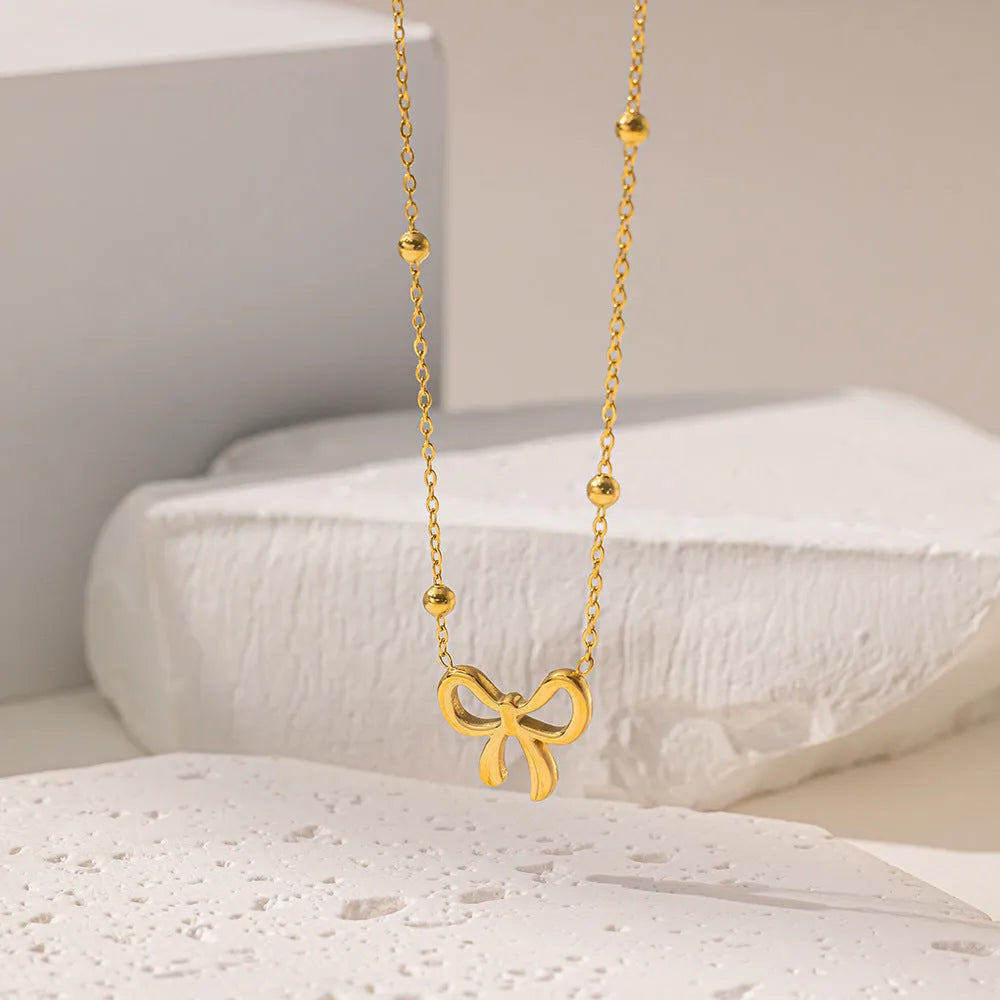 Gold bow necklace with adjustable cross chain on women's neck