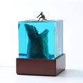 Clear epoxy resin ornament with a detailed shark surfing scene inside, shown next to its integrated lamp holder.