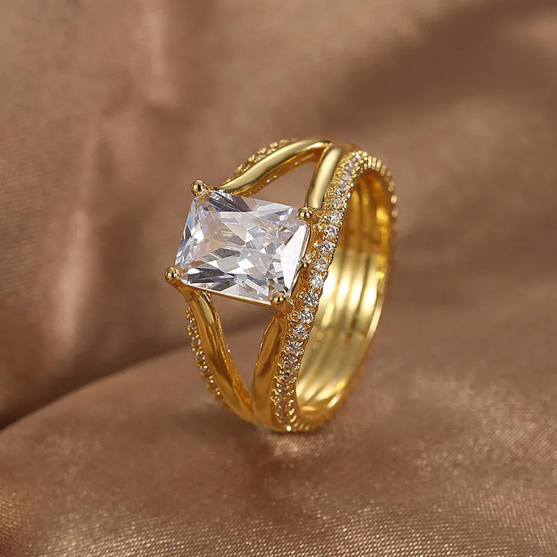 Geometric gold-coloured women's ring with a square zircon stone on a copper band.