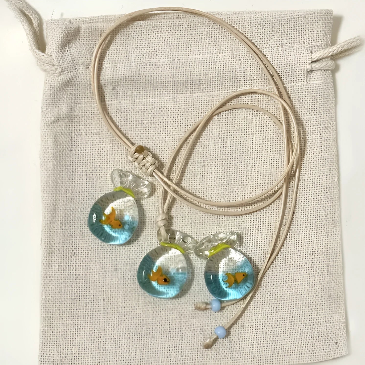 Women's necklace with coloured glaze joker pendant on a beige cotton and linen clavicle chain.