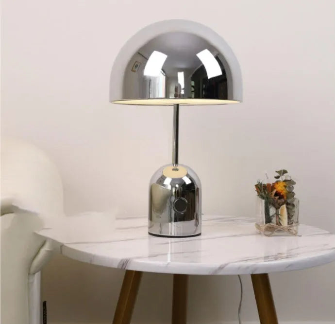 Mushroom-shaped metal table lamp in rose gold finish on a wooden table.
